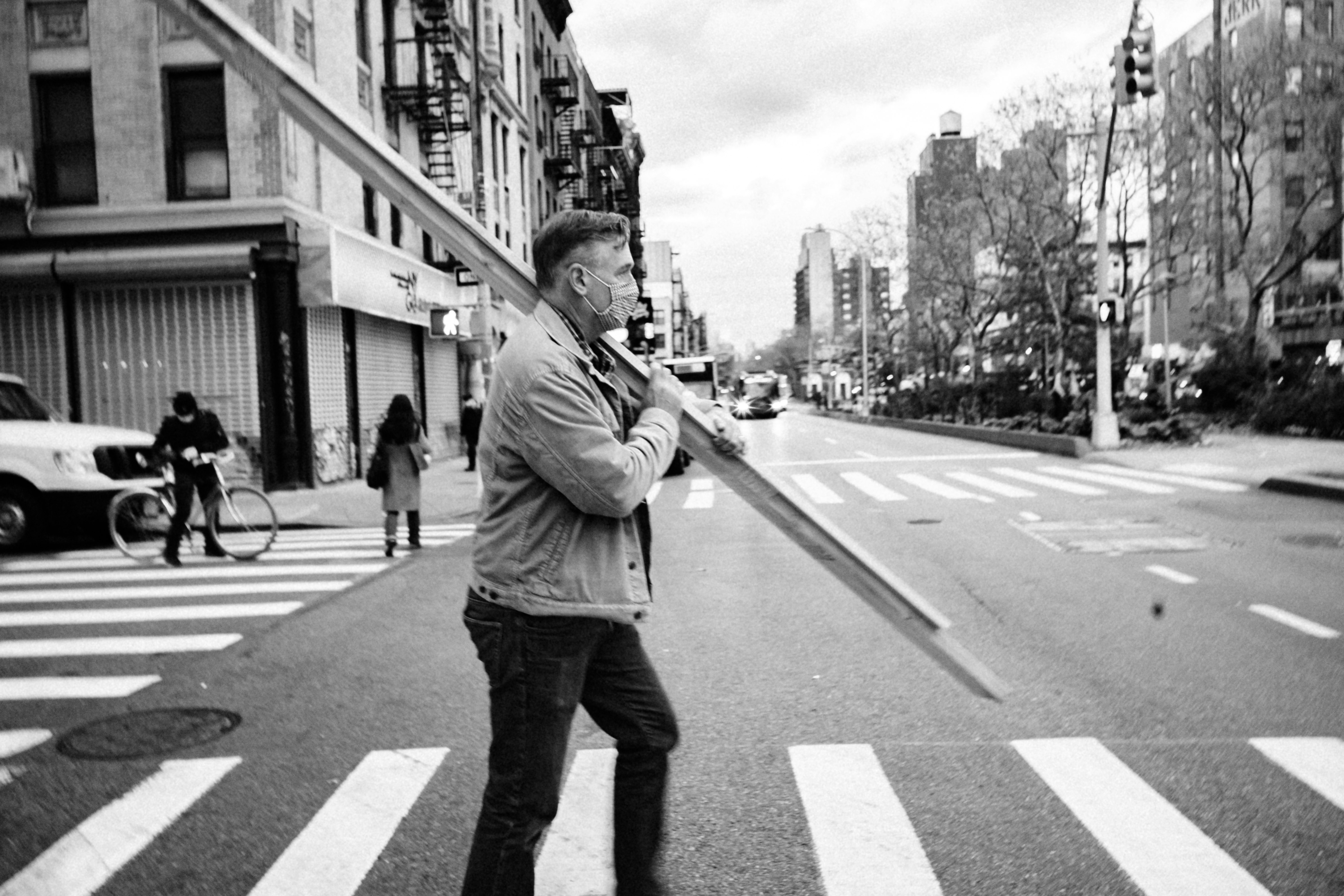 man in gray jacket and black pants standing on pedestrian lane during daytime